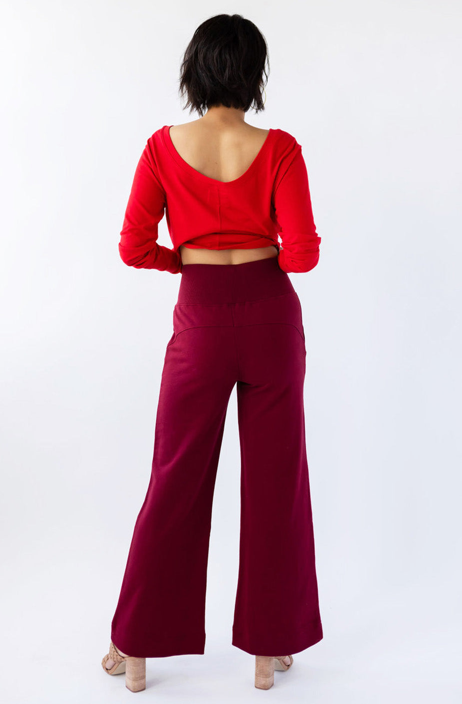 Person wearing a red crop top and burgundy pants on a white background