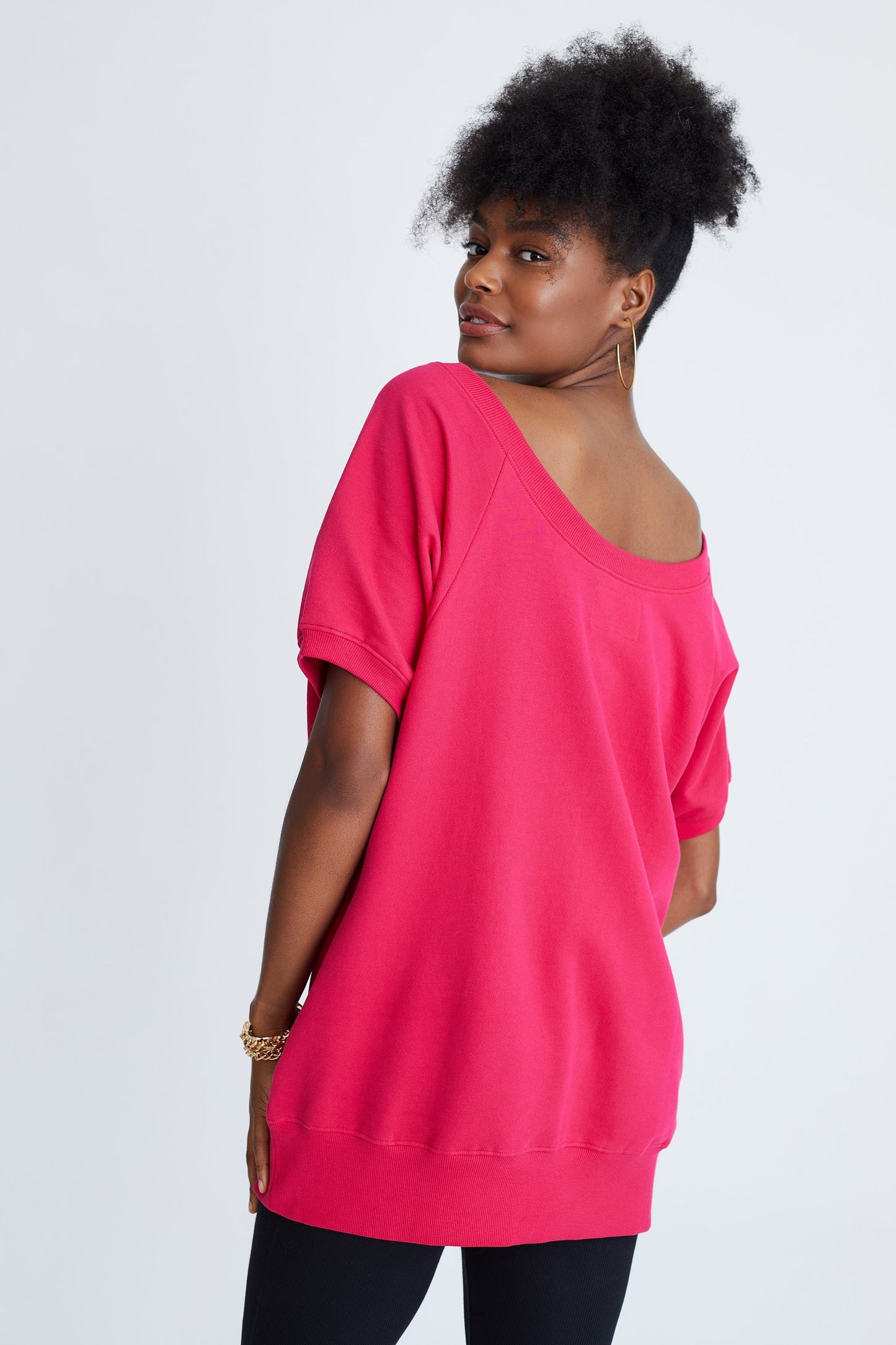 Woman wearing a bright pink oversized top on a white background