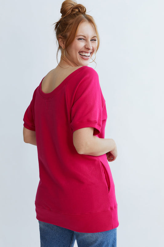 Woman wearing a bright pink top and blue jeans on a white background